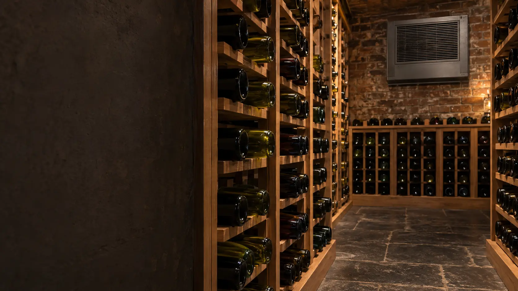 A wine cellar with a through-wall cooling unit and brick walls, seen close and low along the racks.