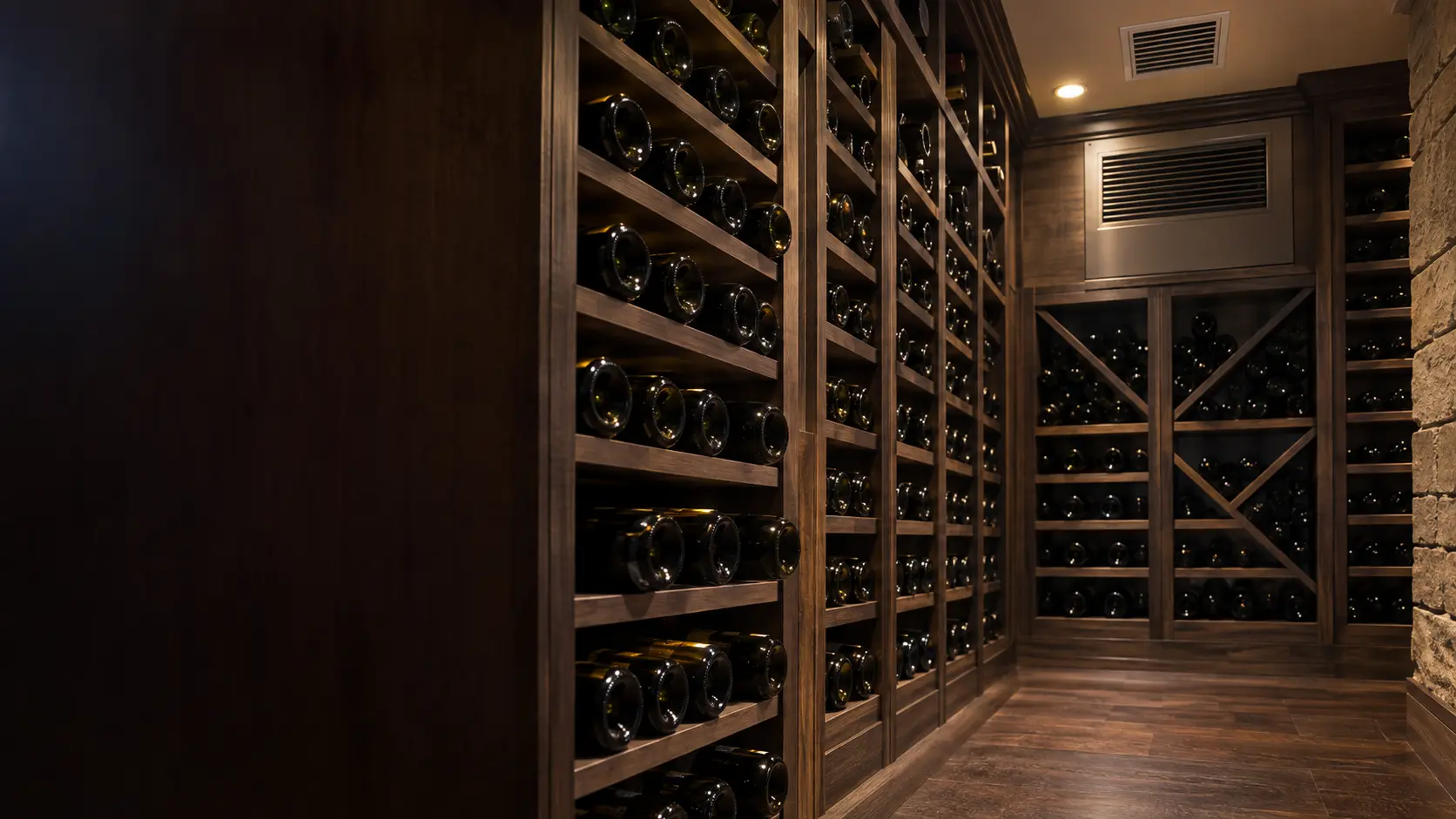 A wine cellar with a ceiling supply grille and dark wood paneling, seen close and low along the racks.