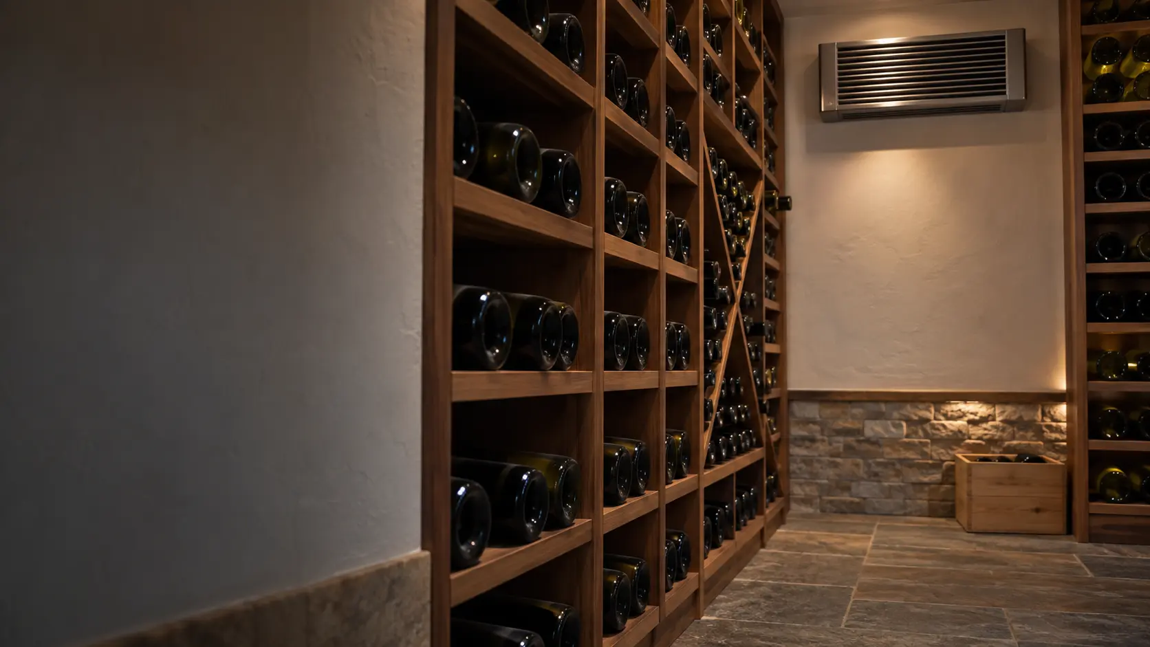 A wine cellar with a wall-mounted evaporator and white plaster walls, seen close and low along the racks.
