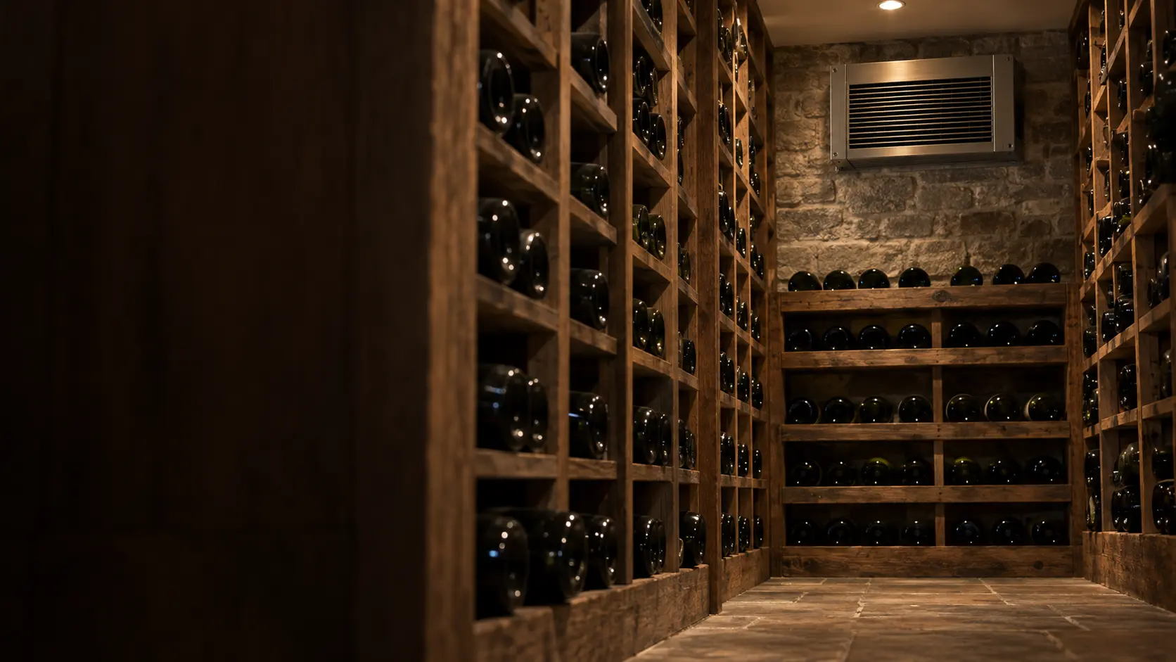 A wine cellar with a wall-mounted evaporator and reclaimed timber, seen close and low along the racks.