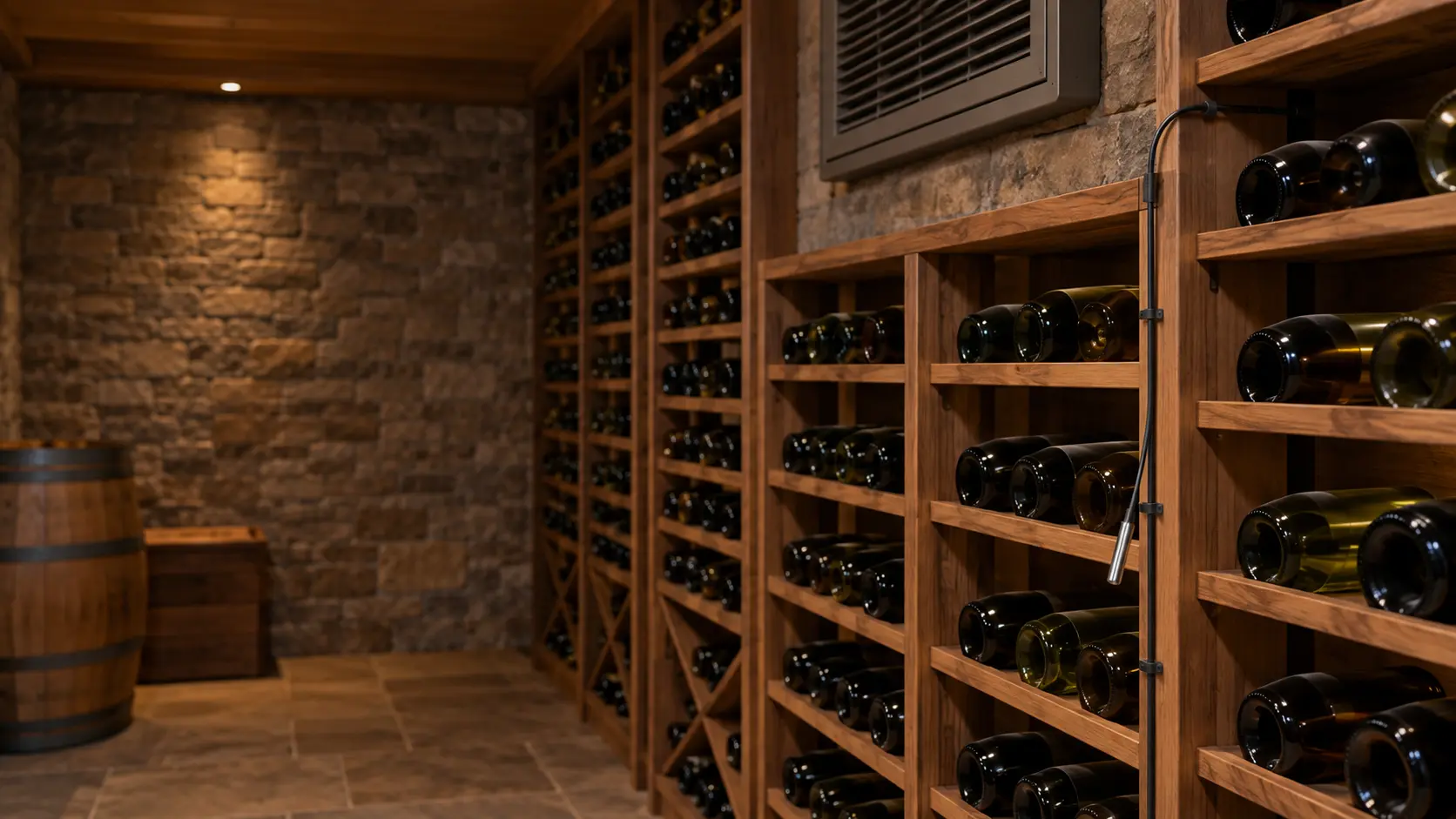A thin temperature probe lead taped along the side of a wooden wine rack in a cellar, its small metal tip hanging among unlabeled bottles, the wire running up toward the cooling unit's grille.