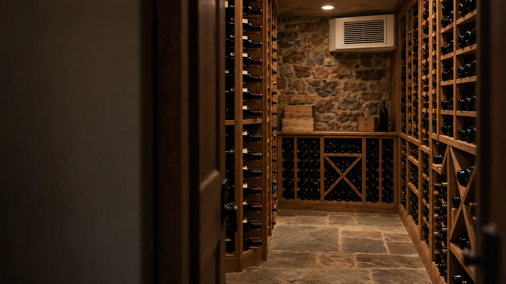 A family home's basement wine cellar with a cooling unit grille high on the far wall, seen from the door.