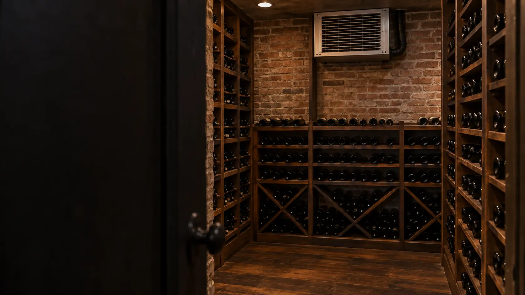 The cooling unit in a New York brownstone's basement wine cellar with brick walls and a cooling unit high on one wall, seen from the cellar door.