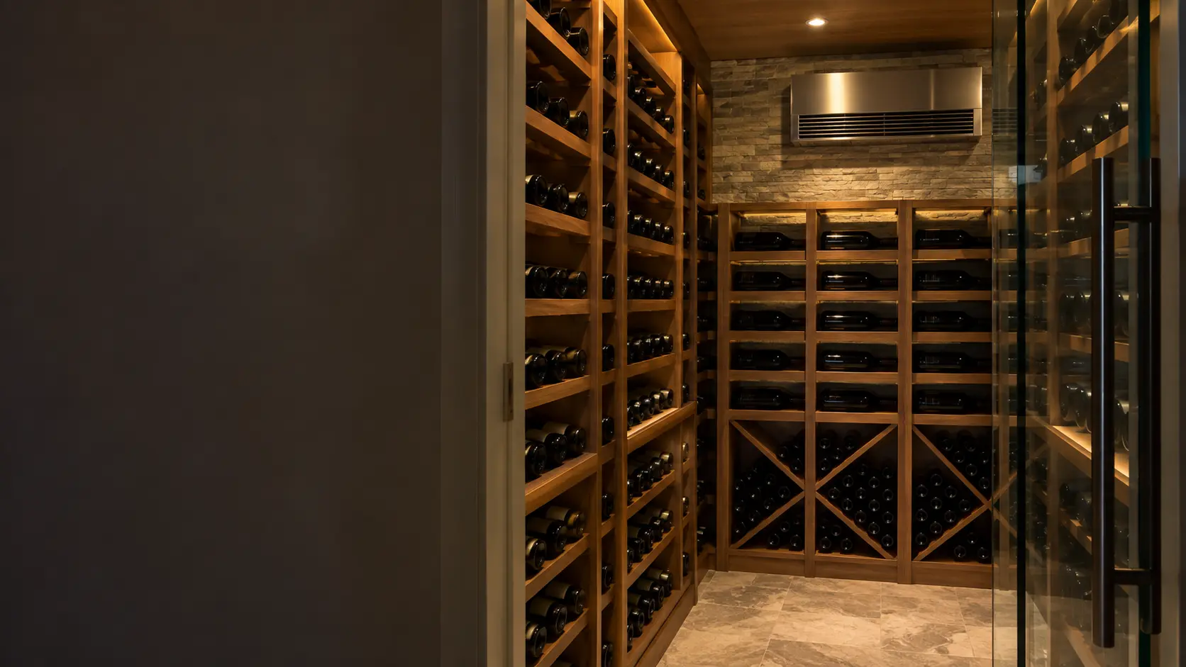 The cooling unit in a Miami condo's small glass wine room with a split-system evaporator on the back wall, seen from the cellar door.
